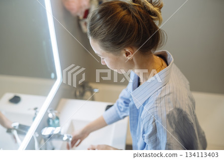 Esthetician meticulously preparing for client in cozy bathroom space 134113403