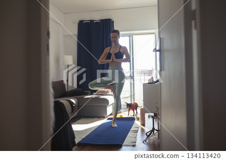 caucasian woman holding tree pose for balance training caucasian woman holding tree pose for balance training 134113420