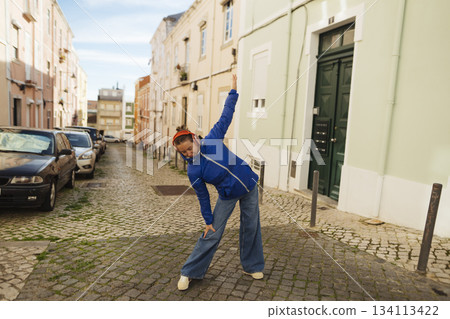 Person engaged in energetic dance on historic city street Person engaged in energetic dance on historic city street 134113422