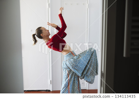 Carefree young woman enjoying vibrant dance with bright smile 134113435