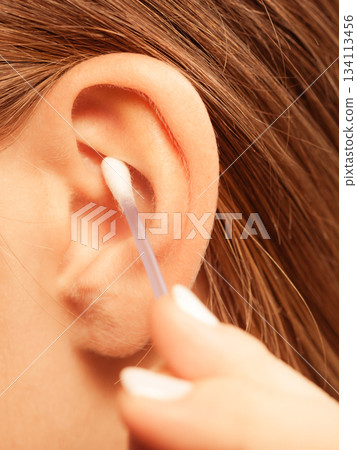 Woman cleaning ear with cotton swabs closeup 134113456