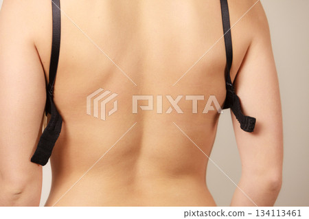 Woman putting on black bra lingerie back view Woman putting on black bra lingerie back view 134113461