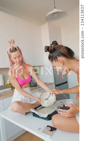 A group of friends joyfully cooking and creating delicious dishes together in a chic modern kitchen 134113637