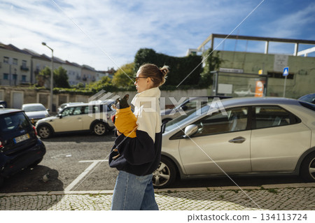 lady departs parking lot, woman in comfortable clothing strides purposefully from parking to downtown lady departs parking lot, woman in comfortable clothing strides purposefully from parking to downtown 134113724