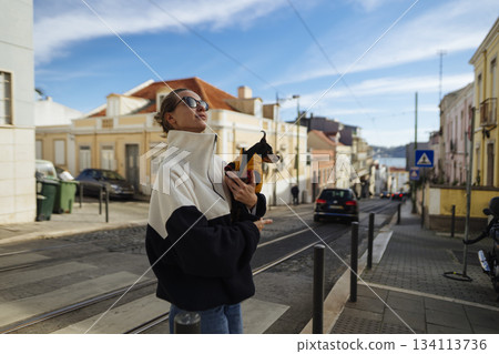 Fashionable pedestrian enjoying bright day amidst lively urban environment 134113736