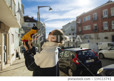 Colorful city backdrop capturing casual moment with woman and dog Colorful city backdrop capturing casual moment with woman and dog 134113741