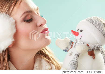 Cute woman kissing little snowman. Winter fashion. Cute woman kissing little snowman. Winter fashion. 134113800
