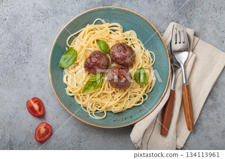 Delicious spaghetti with meatballs on plate, tomato sauce and basil on gray background top view Delicious spaghetti with meatballs on plate, tomato sauce and basil on gray background top view 134113961