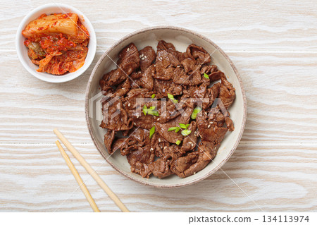 Bulgogi, grilled marinated beef Korean dish with kimchi and sesame seeds top view on white wooden background Bulgogi, grilled marinated beef Korean dish with kimchi and sesame seeds top view on white wooden background 134113974