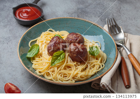 Delicious spaghetti with meatballs on plate, tomato sauce and basil on gray background top view Delicious spaghetti with meatballs on plate, tomato sauce and basil on gray background top view 134113975