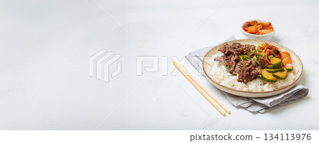 Korean beef bulgogi bowl dish with rice, roasted meat, kimchi and marinated cucumber on white background with chopsticks, space for text Korean beef bulgogi bowl dish with rice, roasted meat, kimchi and marinated cucumber on white background with chopsticks, space for text 134113976