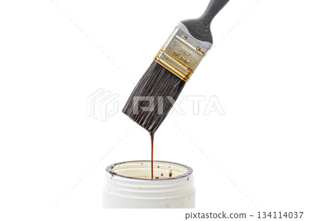 A black bristle paint brush is placed over a can of white lacquer with lacquer dripping from the brush back into the can A black bristle paint brush is placed over a can of white lacquer with lacquer dripping from the brush back into the can 134114037