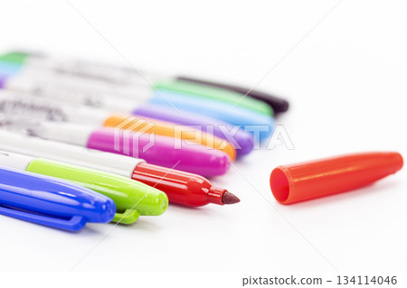 Close-up of colorful markers lined up on a white background with an uncapped red marker and its red cap beside it Close-up of colorful markers lined up on a white background with an uncapped red marker and its red cap beside it 134114046