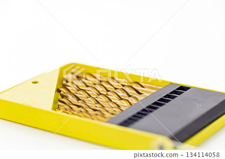 Set of gold metal drill bits arranged neatly in a bright yellow plastic case with a black organizer section on a white background Set of gold metal drill bits arranged neatly in a bright yellow plastic case with a black organizer section on a white background 134114058