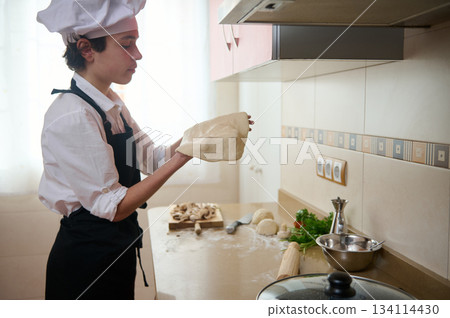 Teen Chef Preparing Pizza Dough In Home Kitchen With White Hat And Black Apron 134114430
