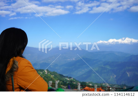 Woman Admires Majestic Kanchenjunga Mountains with Blue Sky 134114612