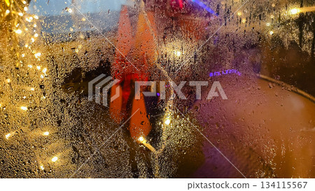 Abstract background of warm bokeh lights and vibrant colors seen through a rain covered window pane Abstract background of warm bokeh lights and vibrant colors seen through a rain covered window pane 134115567