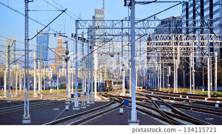 Warsaw, Poland. 28 November 2025. A passenger train on the tracks near the station. Tracks, electrical wires and metal masts against the backdrop of a city skyscrapers on a winter day. Warsaw, Poland. 28 November 2025. A passenger train on the tracks near the station. Tracks, electrical wires and metal masts against the backdrop of a city skyscrapers on a winter day. 134115721