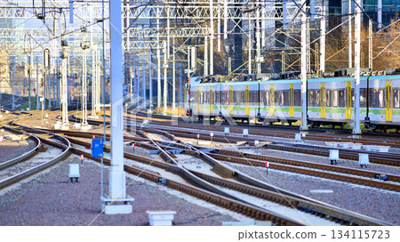 Warsaw, Poland. 28 November 2025. A passenger train on the tracks near the station. Tracks, electrical wires and metal masts against the backdrop of a city skyscrapers on a winter day. Warsaw, Poland. 28 November 2025. A passenger train on the tracks near the station. Tracks, electrical wires and metal masts against the backdrop of a city skyscrapers on a winter day. 134115723