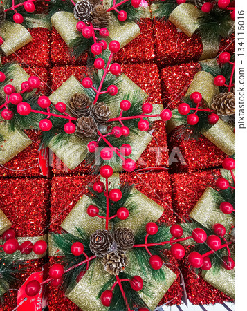Seamless festive background featuring a repeating pattern of wrapped gift boxes, golden bows, pinecones, and red berries. Suitable for holiday cards, seasonal packaging, web design, and Christmas 134116016