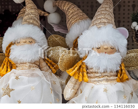Two decorative Scandinavian Christmas gnomes in gold and white tones, wearing tall cone-shaped hats with fluffy white trim and golden accents. Festive holiday ornaments suitable for seasonal decor Two decorative Scandinavian Christmas gnomes in gold and white tones, wearing tall cone-shaped hats with fluffy white trim and golden accents. Festive holiday ornaments suitable for seasonal decor 134116030