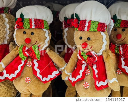Close-up of soft gingerbread-themed toys wearing white chef hats and red jackets. Plush holiday figures suitable for Christmas decorations, seasonal displays, and festive home decor. Close-up of soft gingerbread-themed toys wearing white chef hats and red jackets. Plush holiday figures suitable for Christmas decorations, seasonal displays, and festive home decor. 134116037