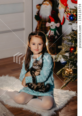 Smiling girl holding kitten beside decorated christmas tree 134116754
