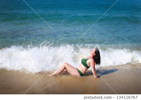 Woman relaxing on the beach enjoying the ocean waves 134116767