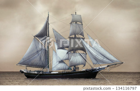 Majestic brig sailing through golden ocean waters under cloudy sky 134116797