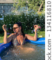 Woman relaxing in inflatable pool splashing water in backyard garden 134116810