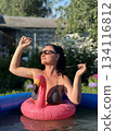 A girl swimming in a pool with an inflatable flamingo 134116812
