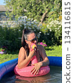 A girl in a swimming pool with a floating inflatable flamingo 134116815