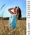 Young woman wearing sunglasses enjoying sunny day in wheat field 134116816