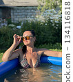 Woman with sunglasses enjoying summer day in inflatable pool 134116818