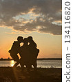 Children kissing mother at sunset on the beach: silhouette of family love 134116820