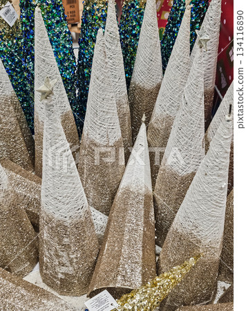 Photo of a set of decorative Christmas cones or stylized trees covered in gold glitter. Festive ornaments suitable for holiday displays, seasonal decor, and Christmas-themed projects. 134116890
