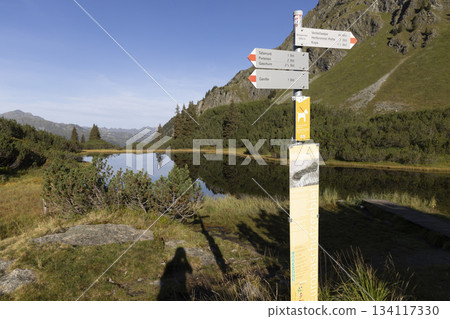 Hiking trail signs near Lake Wiegensee in Gaschurn, Montafon, Vorarlberg, Austria with clear reflections in the water Hiking trail signs near Lake Wiegensee in Gaschurn, Montafon, Vorarlberg, Austria with clear reflections in the water 134117330