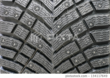 Studded winter tire tread pattern showing deep grooves and metal studs for icy road traction Studded winter tire tread pattern showing deep grooves and metal studs for icy road traction 134117649
