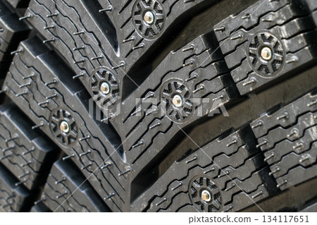 Extreme close-up studded winter tire tread showing detailed rubber pattern and metal traction studs 134117651