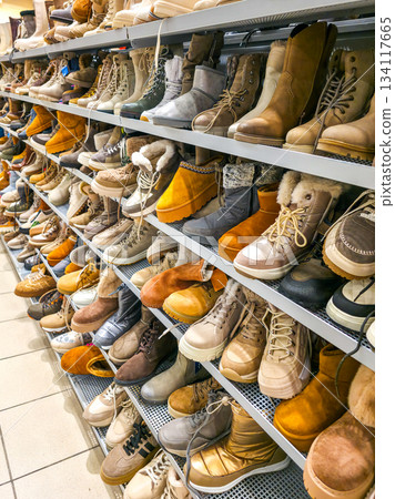 Rows of winter boots and shoes neatly displayed on store shelves inside retail footwear department 134117665