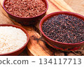 set of red and black and white rice, in a bowl, on a wooden surface, rustic style, top view 134117713