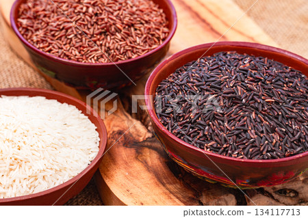 set of red and black and white rice, in a bowl, on a wooden surface, rustic style, top view 134117713
