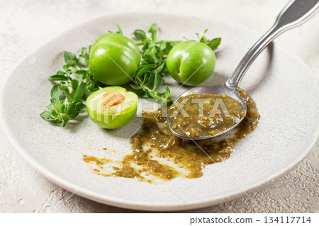 a spoon with tkemali sauce, on a plate, with cherry plum and mint, top view, no people, a spoon with tkemali sauce, on a plate, with cherry plum and mint, top view, no people, 134117714