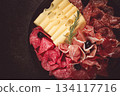 Cold cuts, appetizer, prosciutto, salami and ham, with maasdam cheese and olives, on a round plate, breakfast, top view, close-up, deserted 134117716