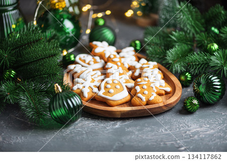 Homemade Decorated Gingerbread Cookies with Icing on Wooden Plate and Pine Decor 134117862
