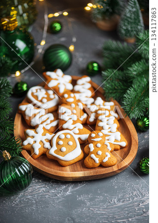 Homemade Decorated Gingerbread Cookies with Icing on Wooden Plate and Pine Decor Homemade Decorated Gingerbread Cookies with Icing on Wooden Plate and Pine Decor 134117863