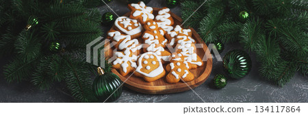 Homemade Decorated Gingerbread Cookies with Icing on Wooden Plate and Pine Decor 134117864
