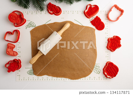 Rolled Cookie Dough with Christmas Holiday Cutters and Rolling Pin on Baking Mat 134117871