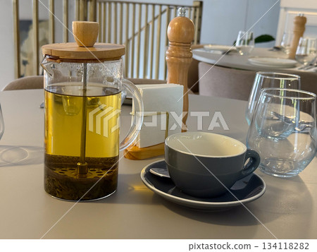 Tea pot with brewing herbs on cafe table. Warm atmosphere, slow living, comfort, lunch break mood. 134118282
