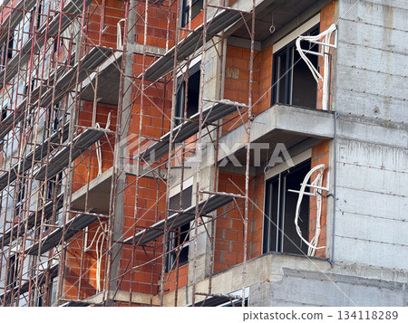 Close view of scaffolding and exposed brick walls on a developing building. Construction phase, architecture framework, unfinished structure, progress, engineering and urban growth. Close view of scaffolding and exposed brick walls on a developing building. Construction phase, architecture framework, unfinished structure, progress, engineering and urban growth. 134118289